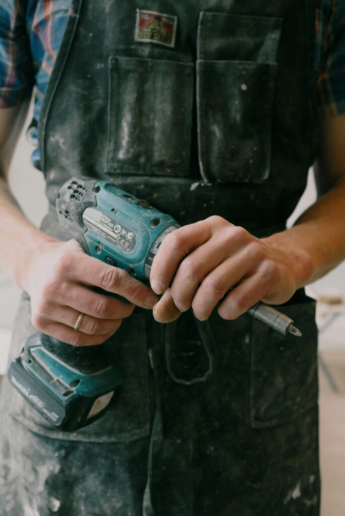 pexels photo 5767926 5767926 Crop anonymous mechanic in uniform with wireless drill standing in flat during repair works